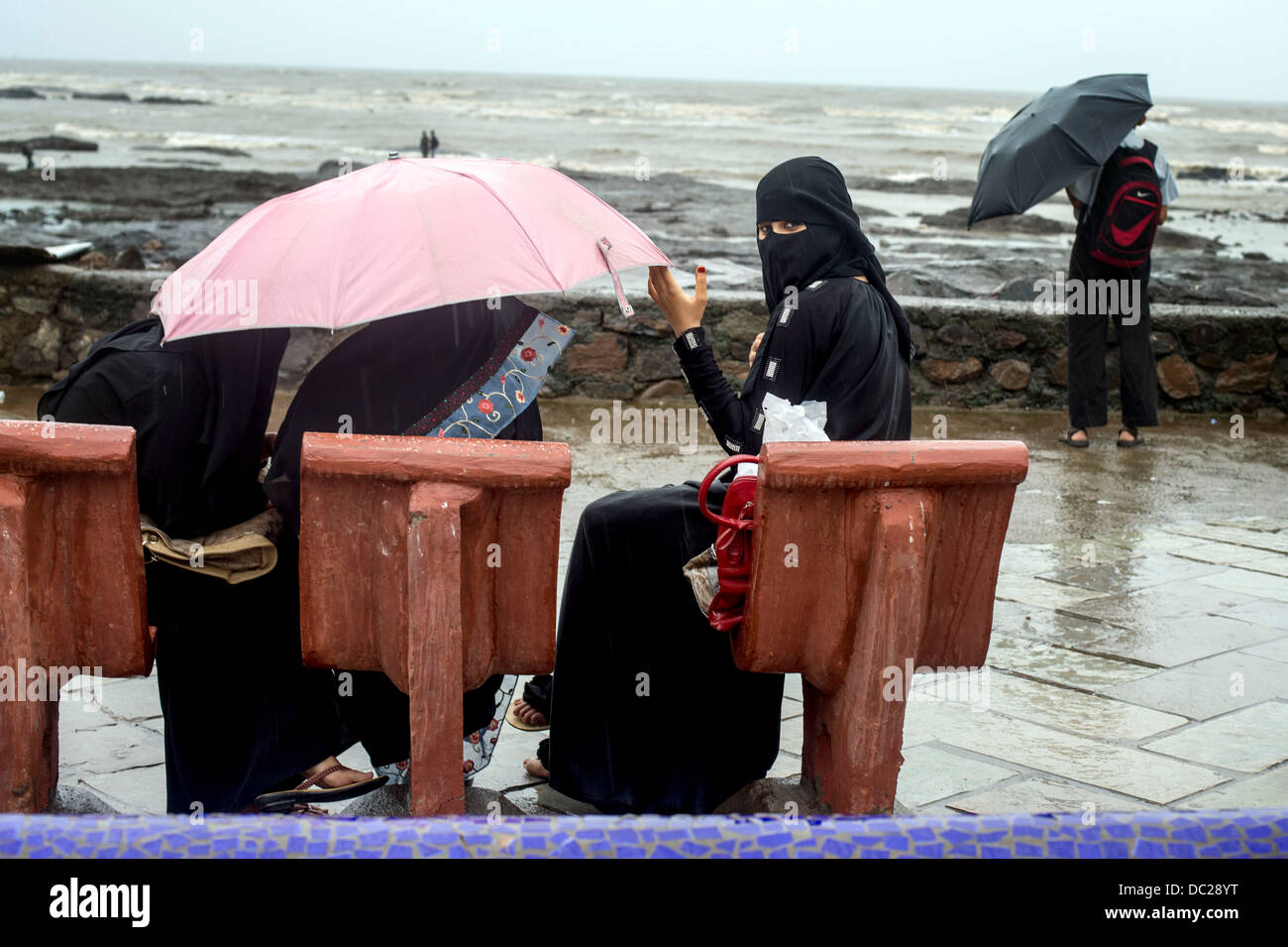 Ragazzina musulmana con ombrello in piogge monsoniche Foto Stock