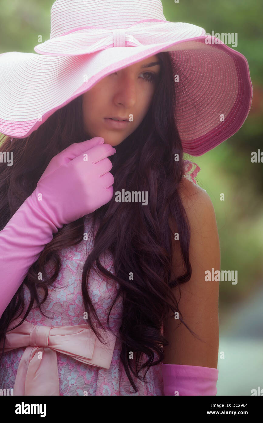 Ritratto di una bellissima ragazza con rosa guanti e cappello per il sole Foto Stock