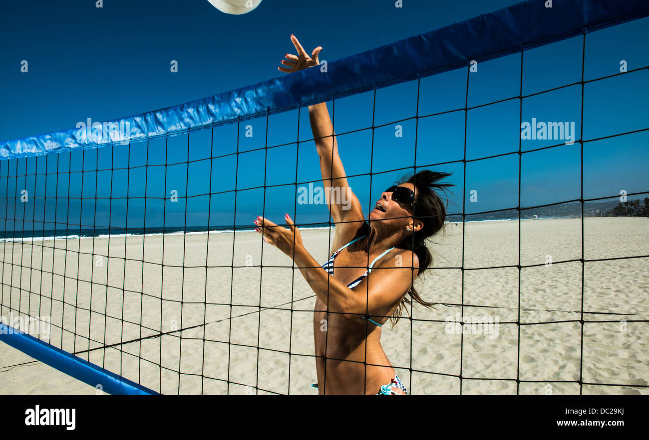 Femmina del giocatore di volleyball della spiaggia di colpire la sfera su net Foto Stock