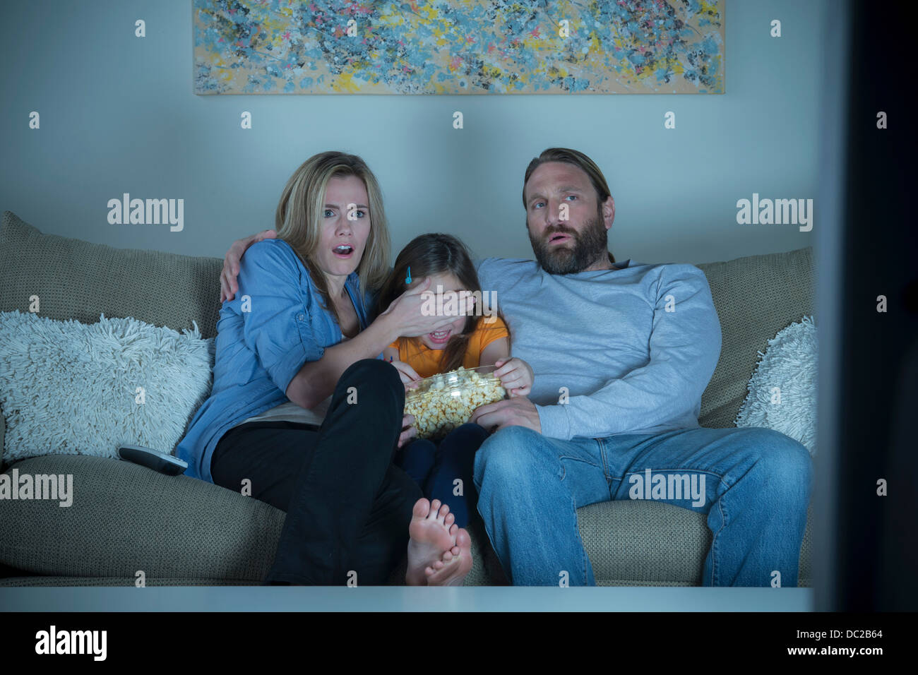 I genitori e il bambino guardando film horror Foto Stock