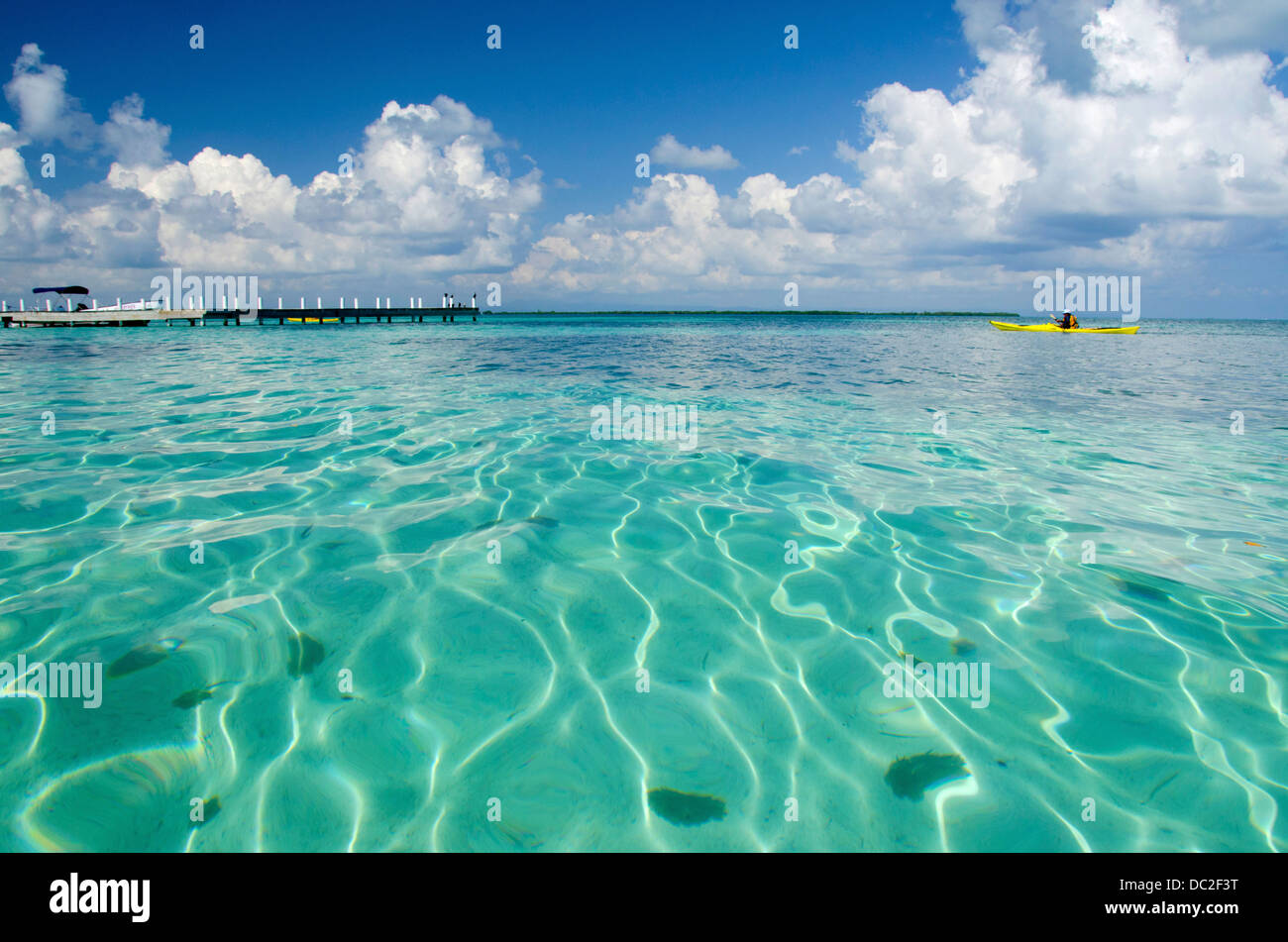 Belize, Stann Creek, Southwater Cay. Blu chiaro con acqua kayaker nella distanza. UNESCO. Foto Stock