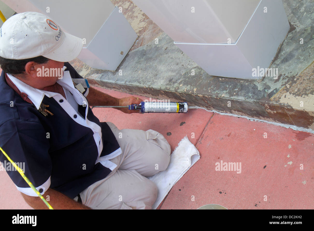 Miami Beach Florida,Ocean Drive,uomo ispanico uomini maschio,manutenzione hotel,caulk,cianfrinatura,riparazione,riparazione,crepe,marciapiede,lavoro,lavoro,cercando FL130 Foto Stock
