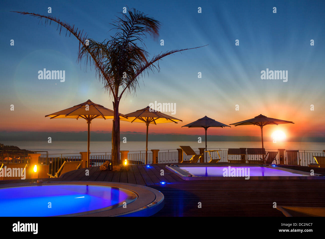 Orario estivo: Beautiful Dawn nella zona piscina con palme e ombrelloni, Tropea, Italia Foto Stock