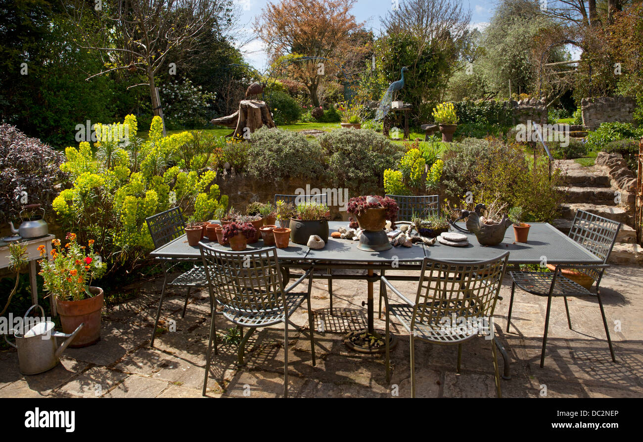 Garden Cottage patio con tavolo in metallo mobili e euphorbia piantagione e piante in vaso, Inghilterra Foto Stock