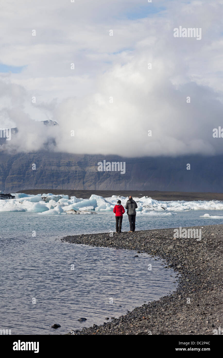 Due persone godendo della vista sulla Jokulsarlon laguna glaciale Vatnajökull Parco Nazionale di Islanda Foto Stock