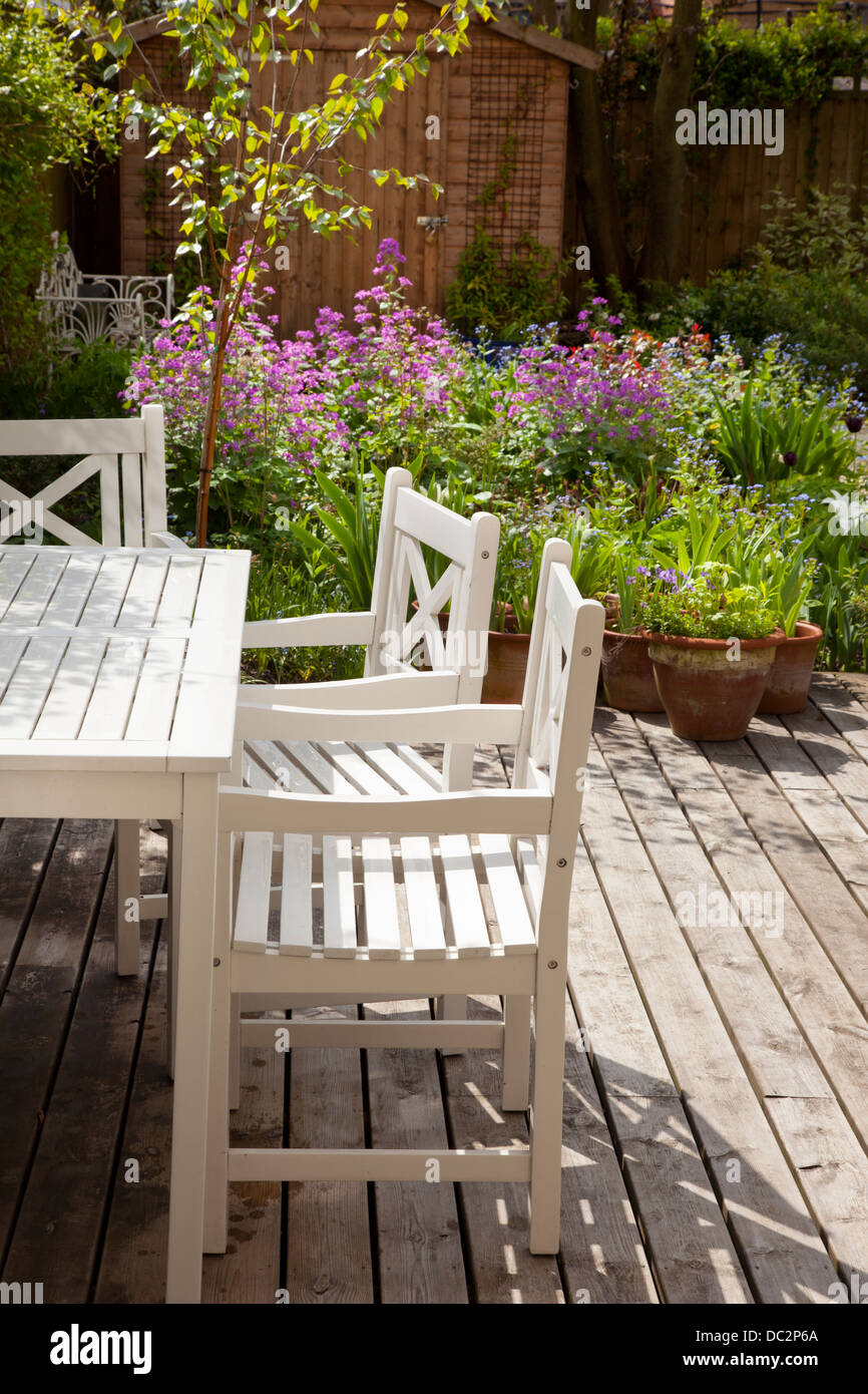 White mobili da giardino in legno e decking con estate boarder nel giardino inglese, Inghilterra Foto Stock