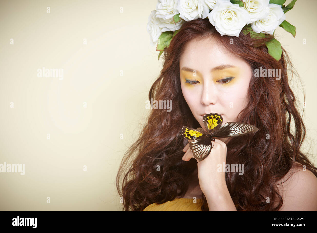 Una signora in abito con ghirlanda di fiori sulla testa in posa con farfalla Foto Stock