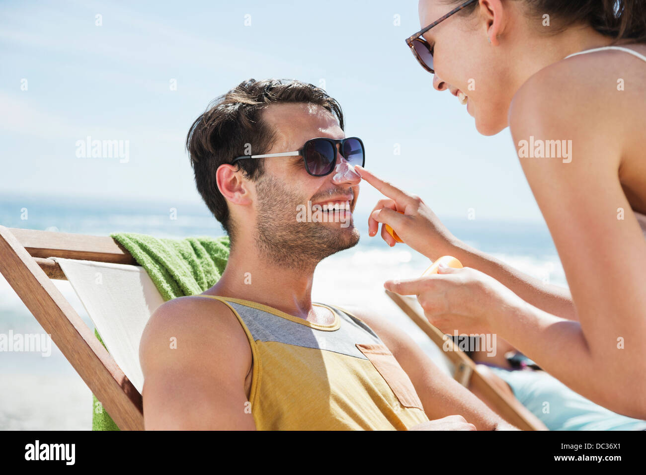 Donna l'applicazione di crema solare per l'uomo del naso a beach Foto Stock