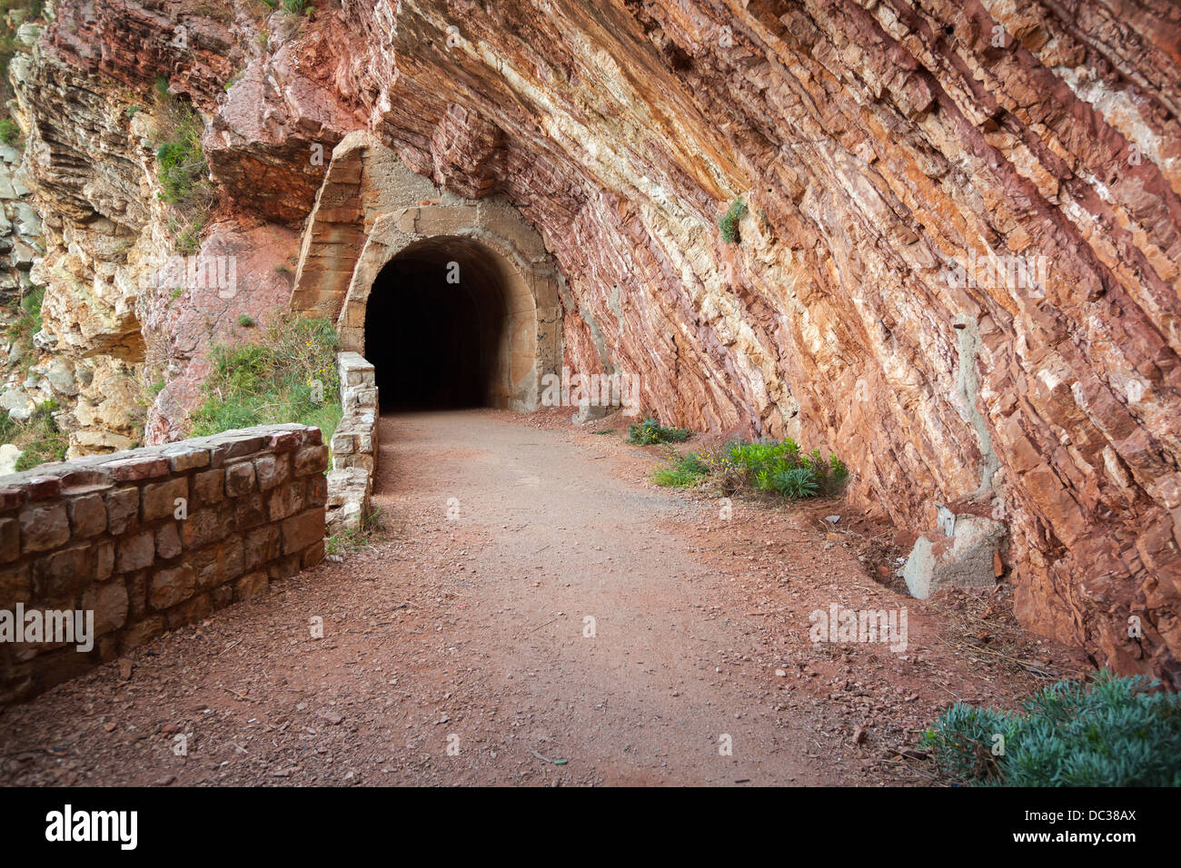 Dark vecchio tunnel entrata in red rock Foto Stock