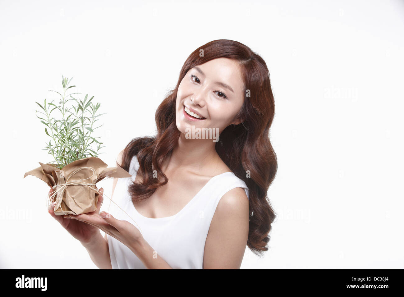 Una signora in abito bianco tenendo un impianto Foto Stock