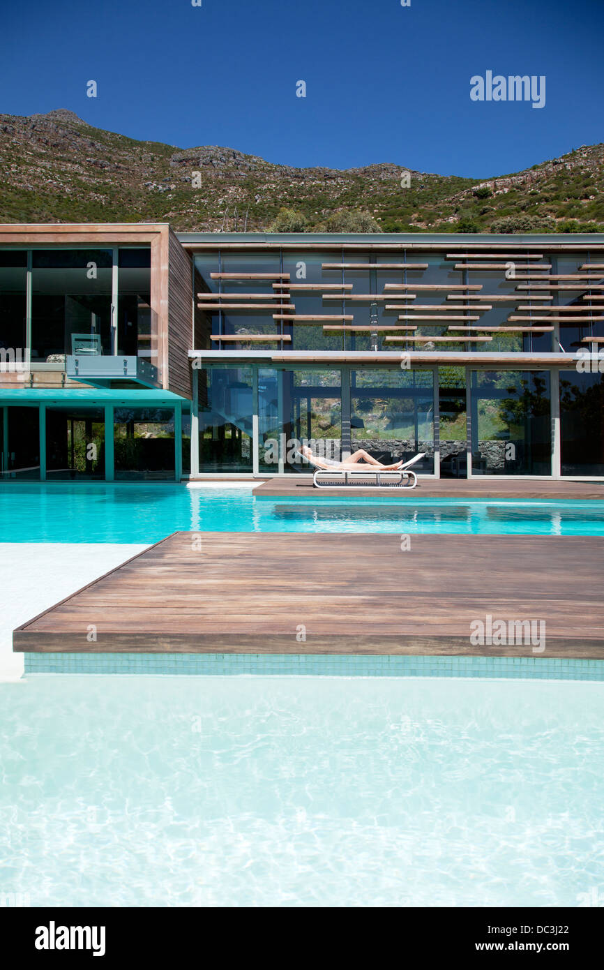 La donna a prendere il sole a bordo piscina di casa moderna Foto Stock