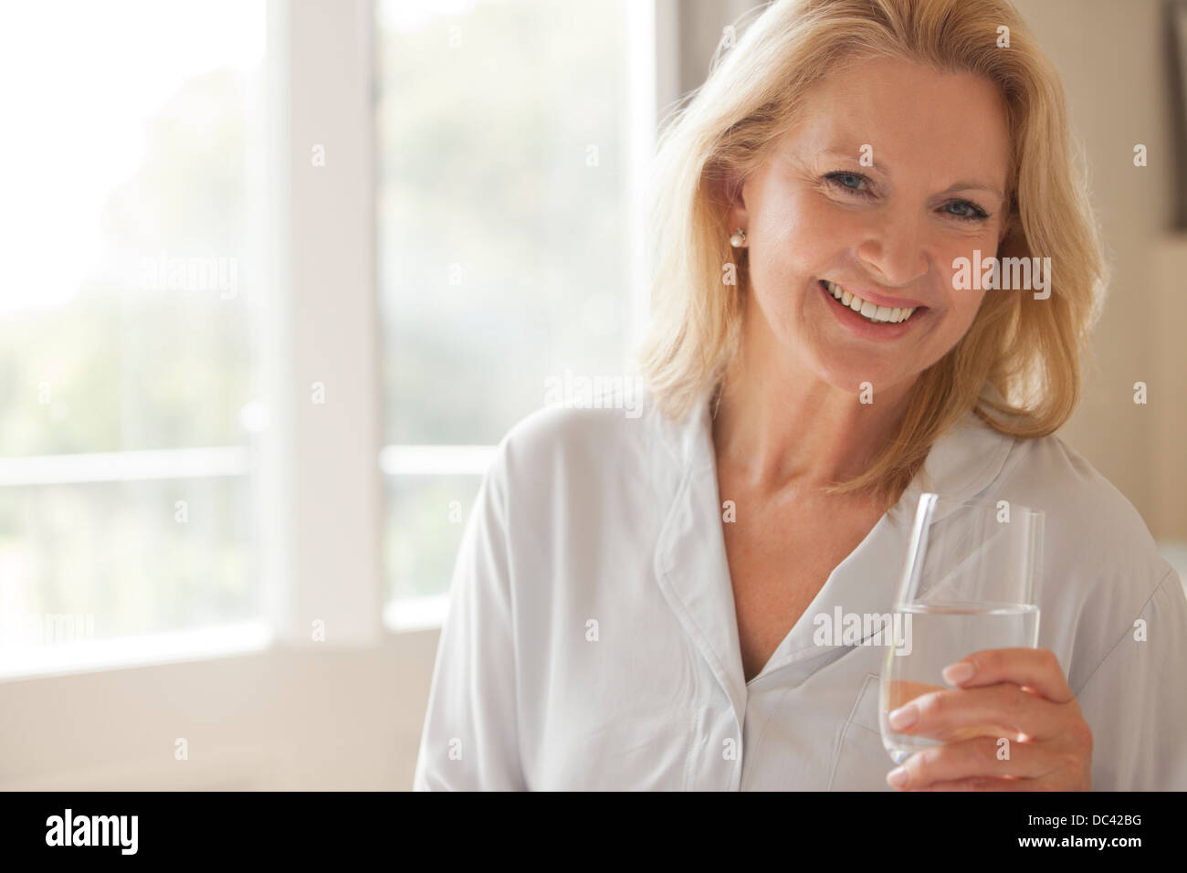 Ritratto di donna sorridente di bere un bicchiere di acqua Foto Stock