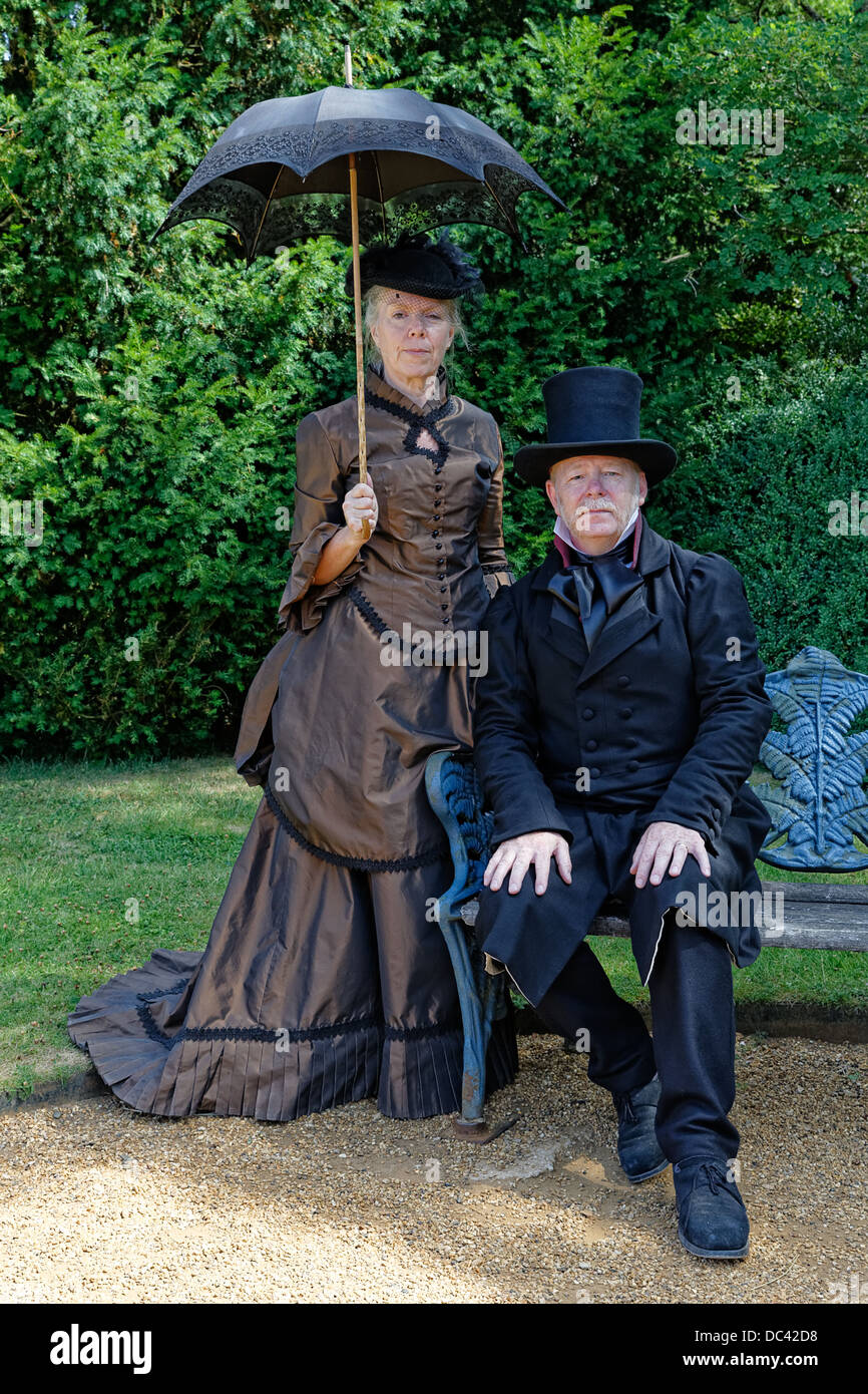 Ricreazione vittoriano Gentleman in top hat doppio petto tonaca rivestire con la signora in abito con la confusione in hat sotto un ombrellone Foto stock Alamy