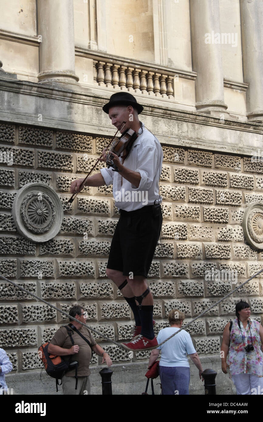 Uomo che cammina su uno stretto mentre suona il violino, Busker / Street Entertainer nel centro di Bath in Inghilterra Foto Stock