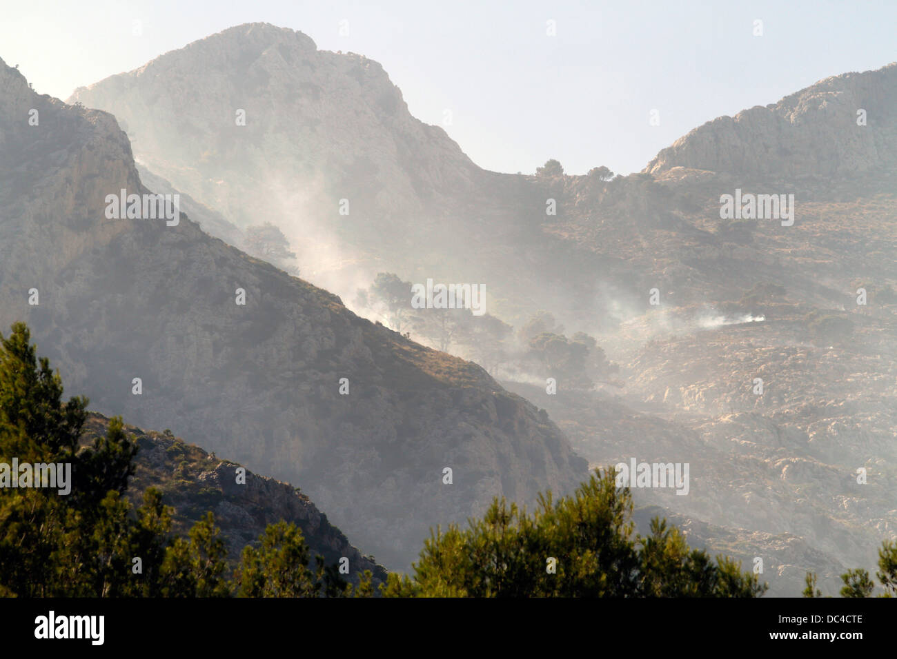 Il fumo vola sopra Estellencs montagne dell'isola di Mallorca dopo una massiccia diffusione di un incendio circa 2300 ettari. Foto Stock