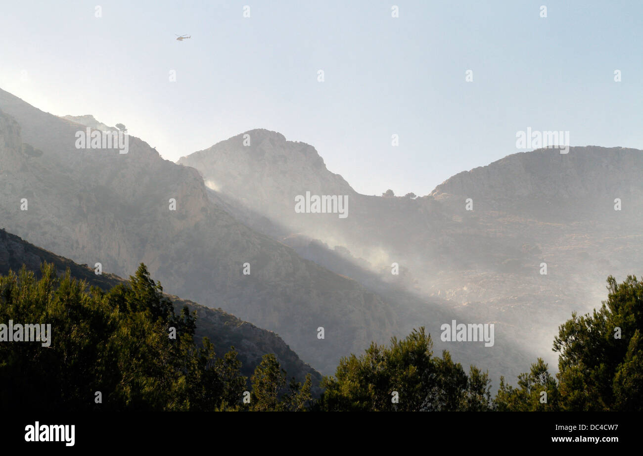 Il fumo vola sopra Estellencs montagne dell'isola di Mallorca dopo una massiccia diffusione di un incendio circa 2300 ettari. Foto Stock