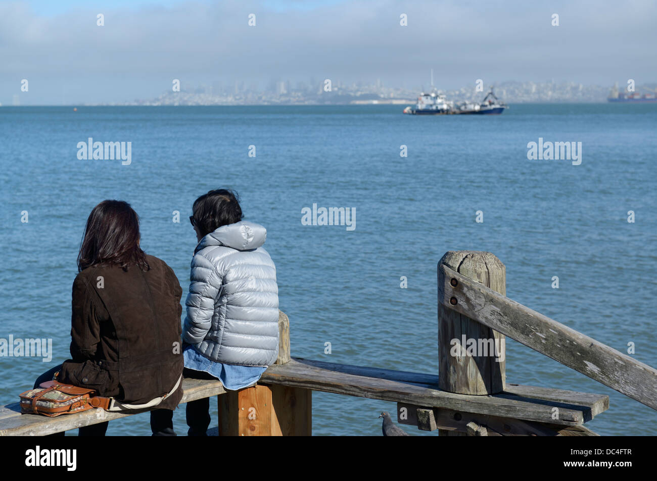 Seduti lungo il lungomare, Sausalito CA con SF in distanza Foto Stock
