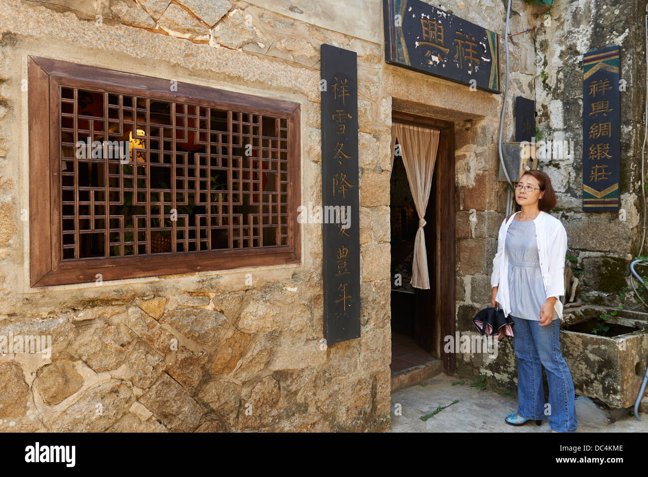 Locale Isola Beigan residente Hao-Lien Wang al di fuori della sua famiglia orientale classico stile Fujian casa di pietra. Foto Stock