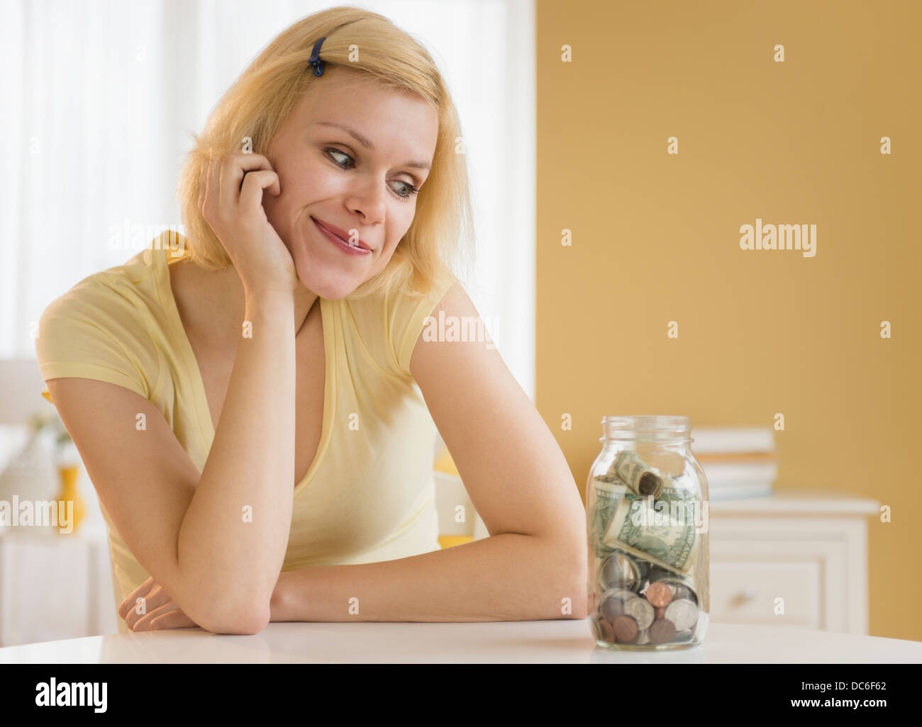 Ritratto di donna guardando il vaso pieno di denaro Foto Stock