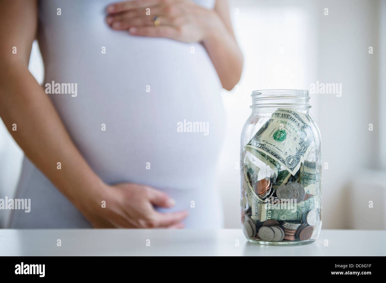 La sezione centrale della donna incinta, jar con denaro di fronte Foto Stock