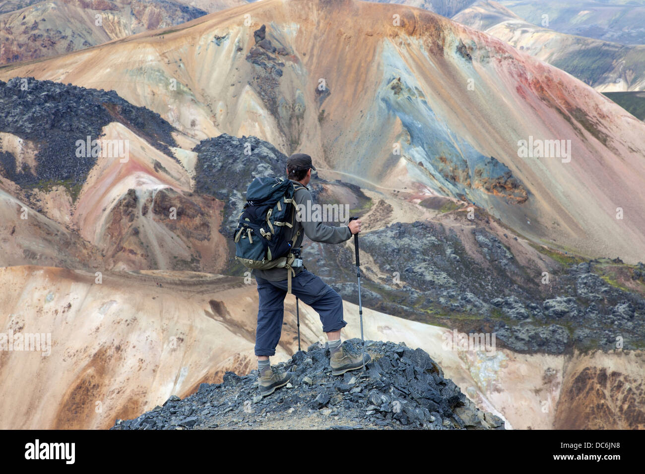 Escursionista sulla montagna di Blahnukur guardando verso il coloratissimo Brennisteinsalda vulcano vicino a Landmannalaugar Islanda Foto Stock