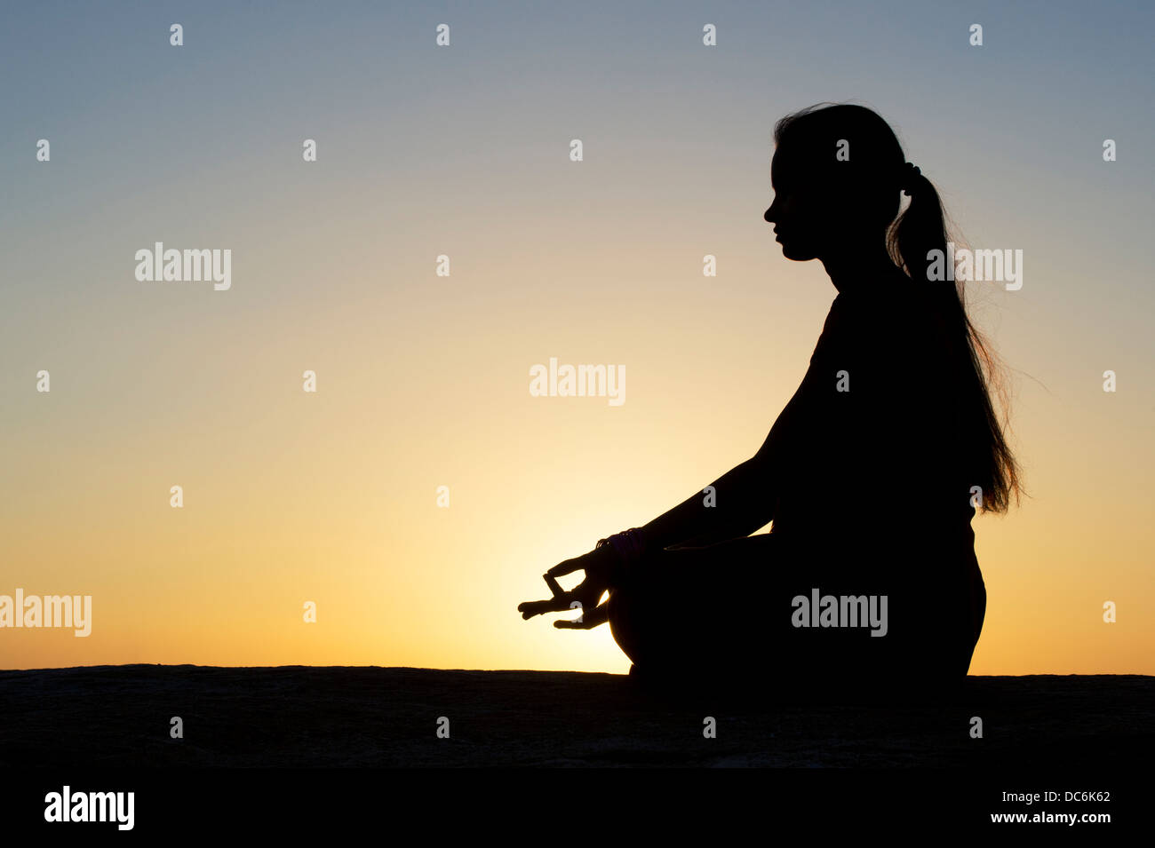 Sunset silhouette di una ragazza indiana meditando. Andhra Pradesh, India Foto Stock