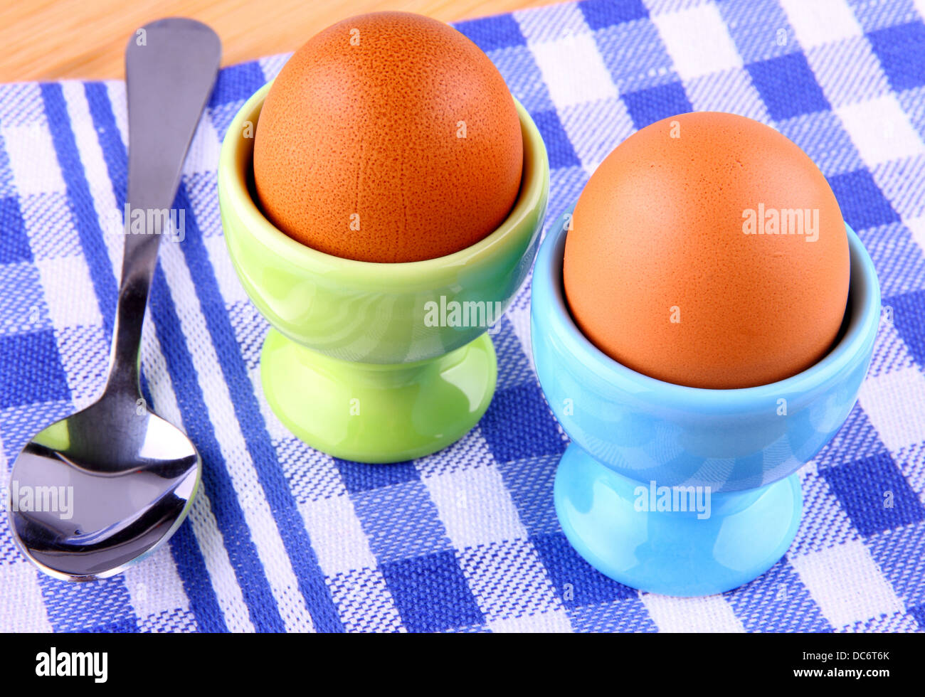 Due uova sode con cucchiaio, a scacchi blu e bianchi Foto Stock