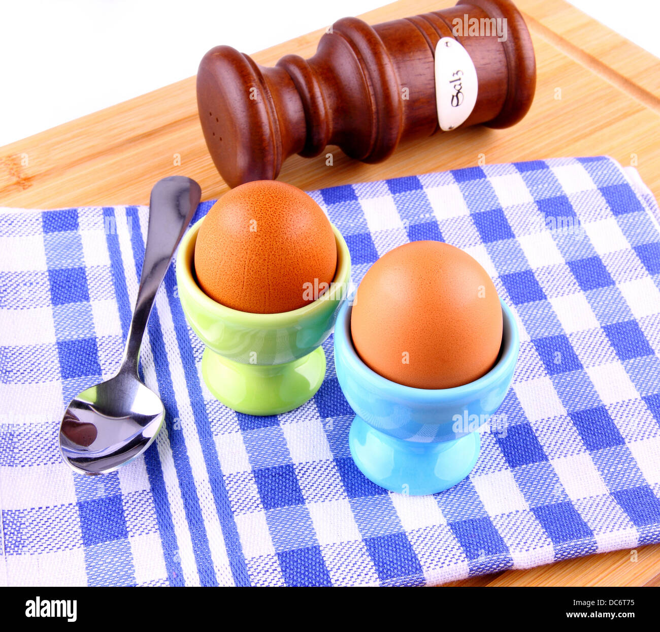 Due uova sode con cucchiaio e sale, a scacchi blu modello bianco Foto Stock