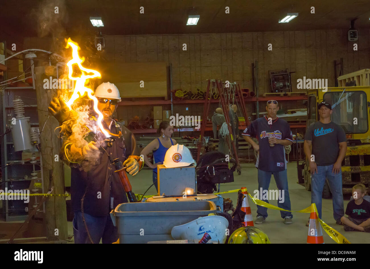 Un'utilità elettrica lineman dimostra la pericolosità di linee elettriche ad alta tensione Foto Stock