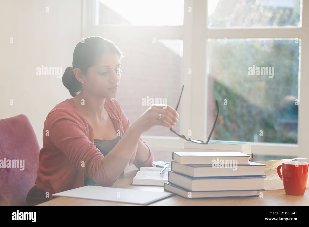 Giovane donna studiando libri a scrivania Foto Stock