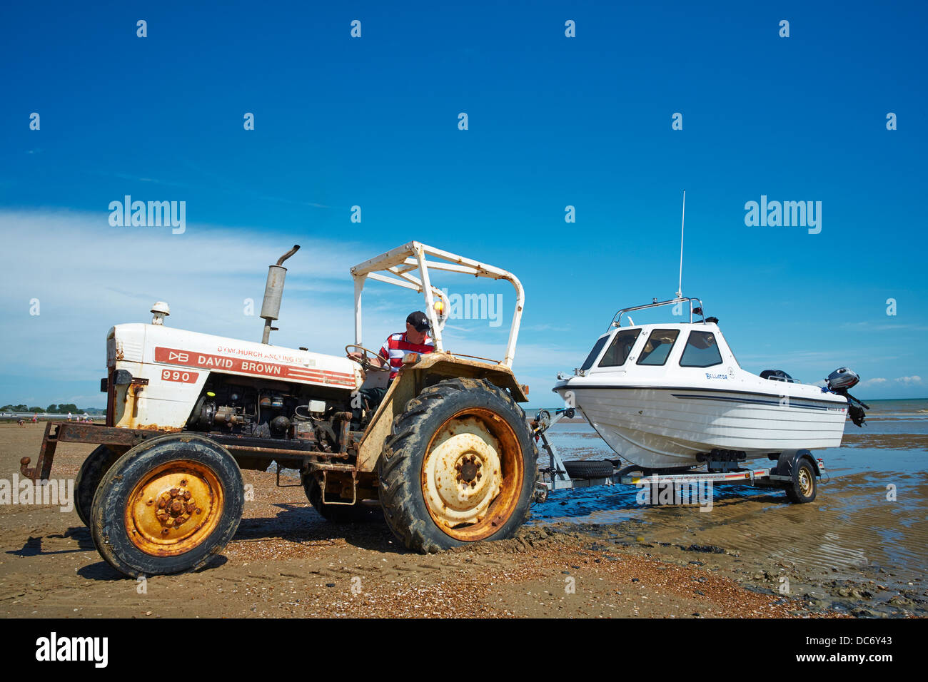 Trattore tirando una piccola barca al di fuori del mare Dymchurch Kent REGNO UNITO Foto Stock
