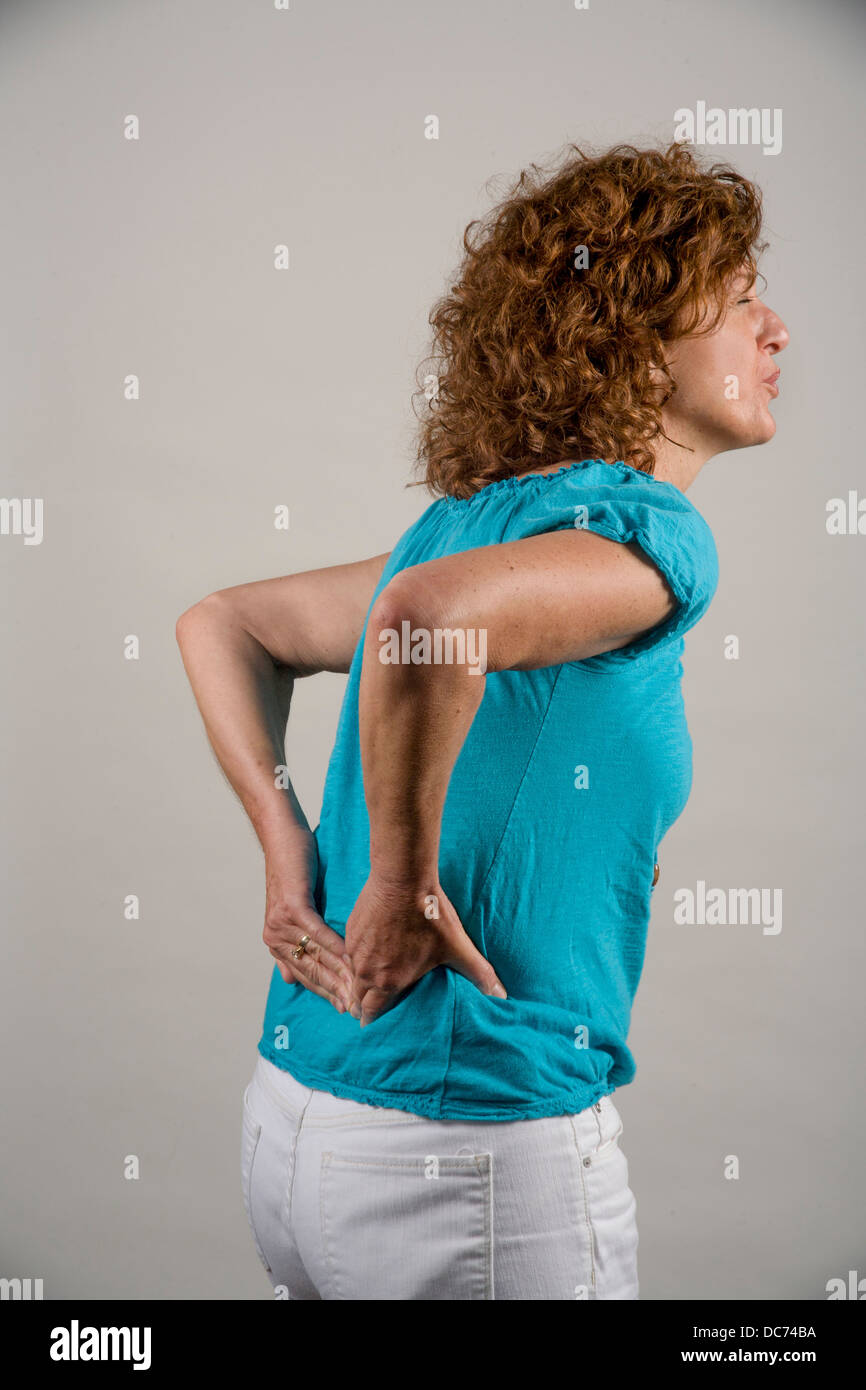 A 50 anni dai capelli rossi donna dimostra i dolori alla parte inferiore della schiena. Foto Stock