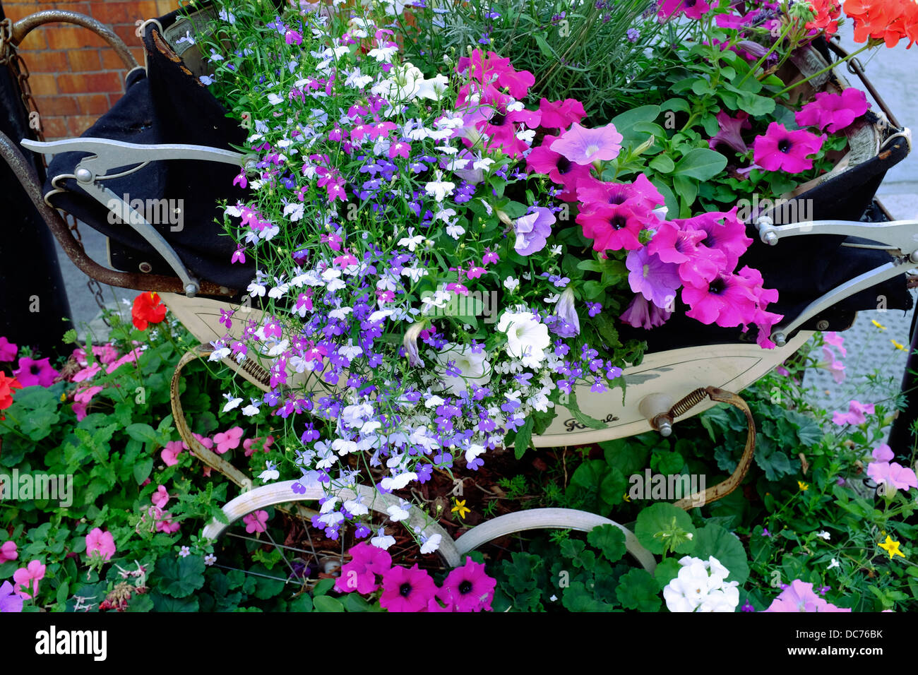 Vecchio pram essendo utilizzato come contenitore per fiori, London REGNO UNITO Foto Stock