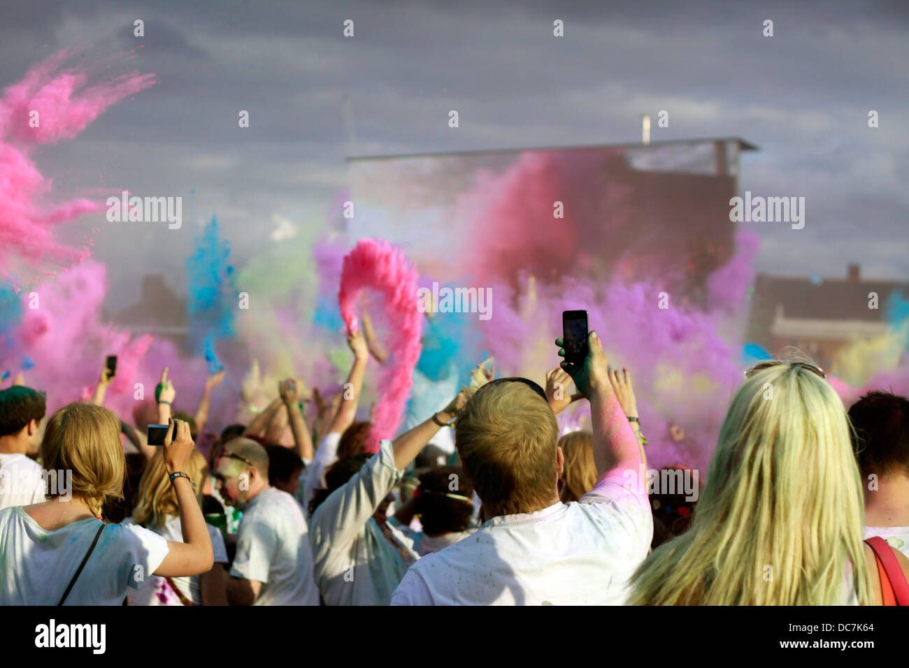 La Folla di gettare la potenza del colore in aria a Holi festival Foto Stock