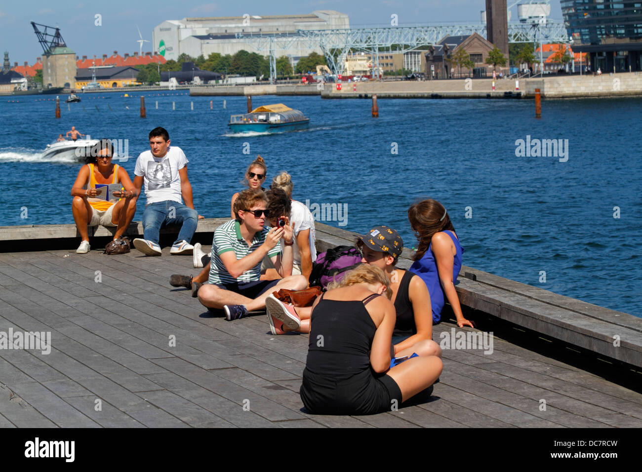 I giovani sul molo presso il Royal Playhouse vicino a Nyhavn porto interno di Copenaghen sul soleggiato e caldo pomeriggio estivo. Anche i visitatori e i turisti Foto Stock