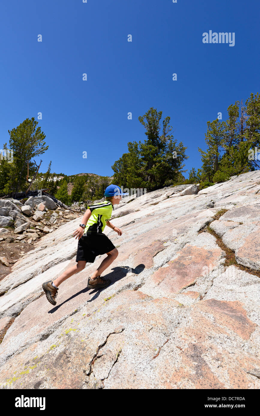 Ragazzo in esecuzione su una ripida pendenza di roccia nel Wallowa Mountains, Oregon. Foto Stock