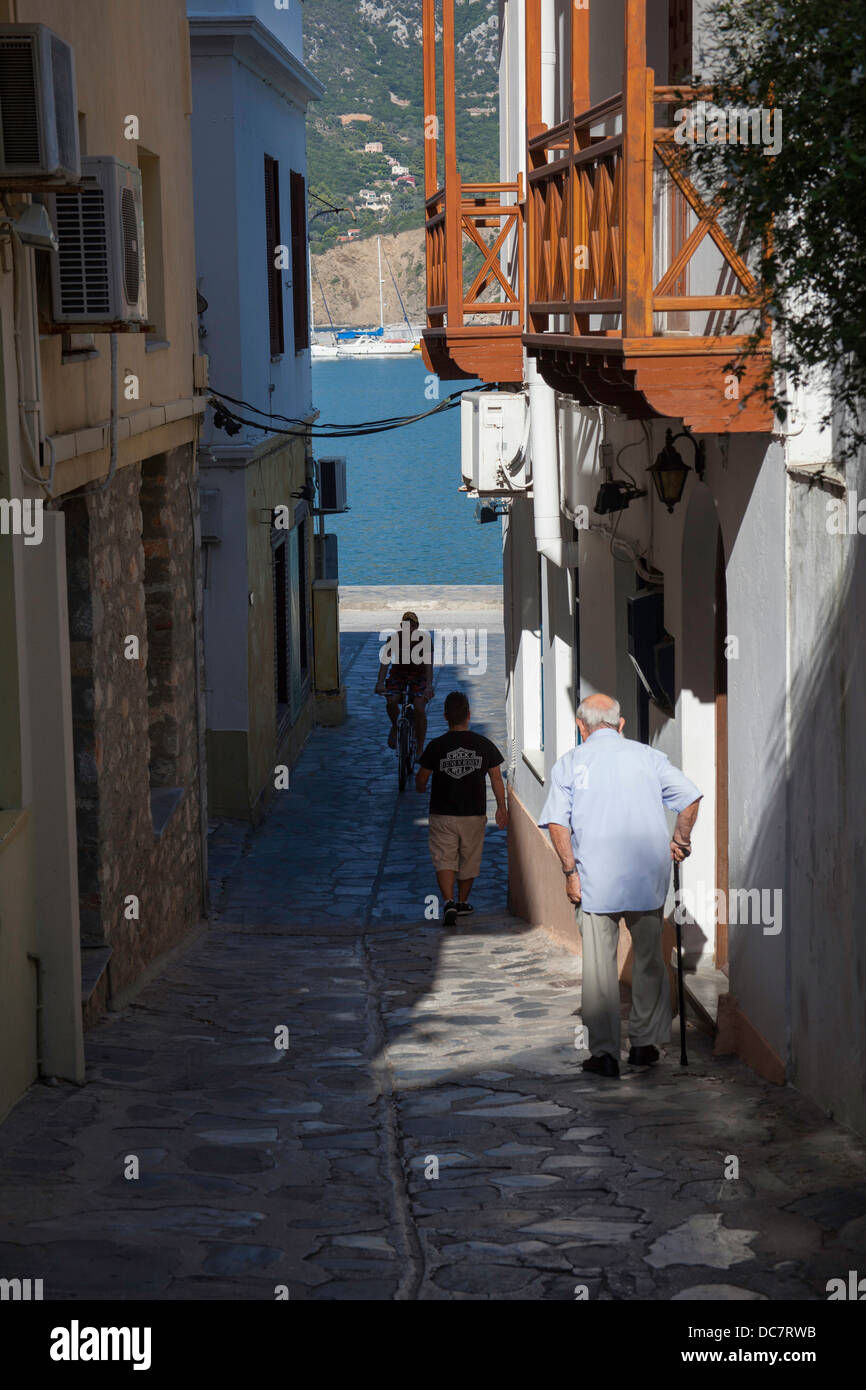 Lato greco street città di Skopelos Grecia vecchio uomo e uomini più giovani in strada Foto Stock