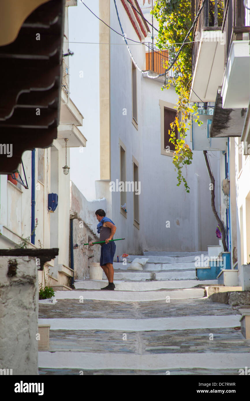 Lato greco street nella città di Skopelos, uomo pareti di pulizia in greco street Foto Stock
