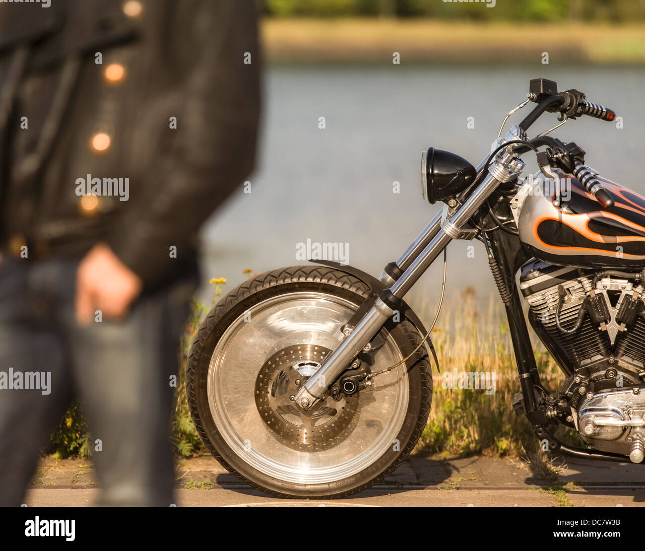 Giovane uomo che indossa indumenti di cuoio Indumenti di cuoio con la sua Harley Davidson Foto Stock