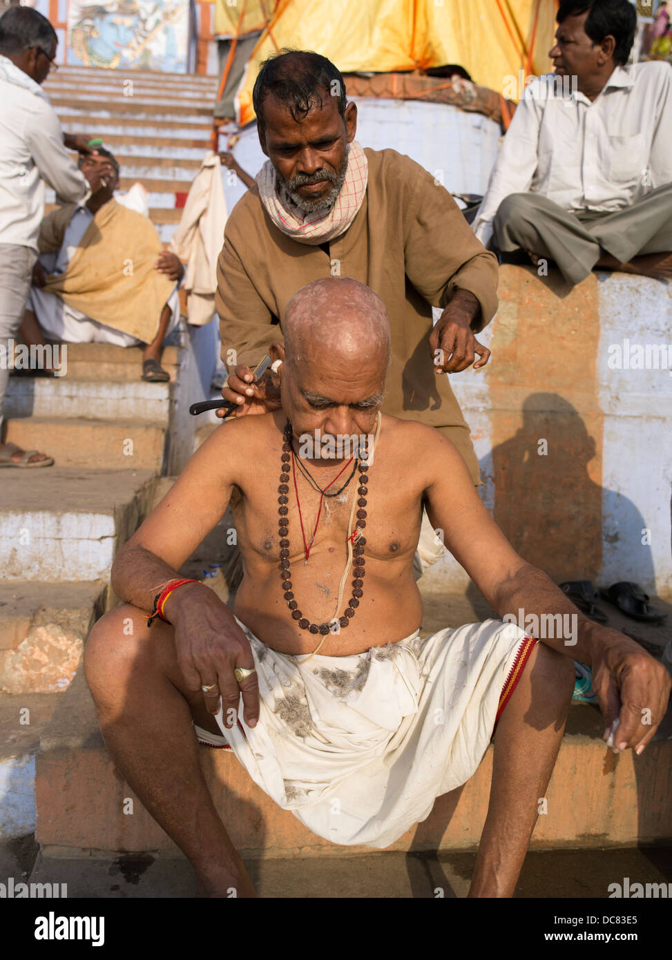 Rasatura mattutina. taglio di capelli. La vita sulle rive del Gange Fiume - Varanasi, India Foto Stock