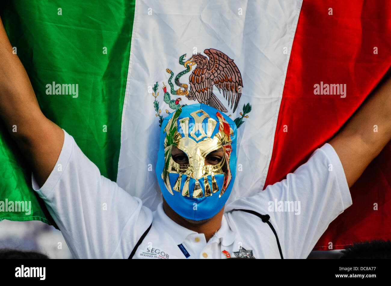 Un uomo che indossa un wrestler messicano la maschera e può contenere fino a bandiera messicana Foto Stock