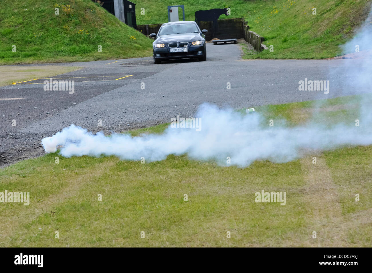 Un fumo e blast granata è gettato nella parte anteriore di una vettura in movimento a disorientate e distrarre il guidatore Foto Stock Un fumo e blast granata è gettato nella parte anteriore di una vettura in movimento a disorientate e distrarre il guidatore Foto Stock