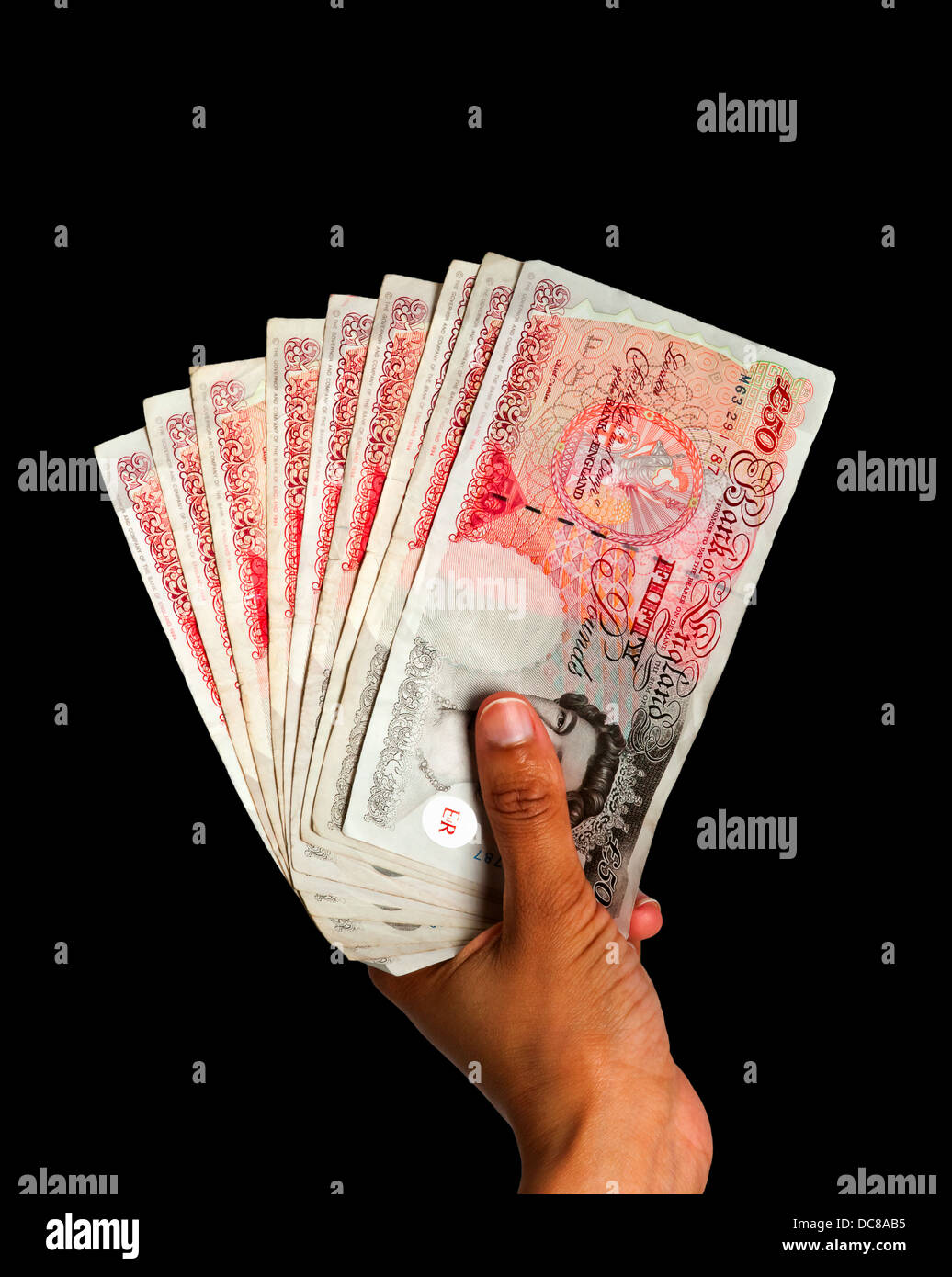 Il denaro posseduto in mano - La valuta britannica con percorso di clipping - Sfondo nero Foto Stock