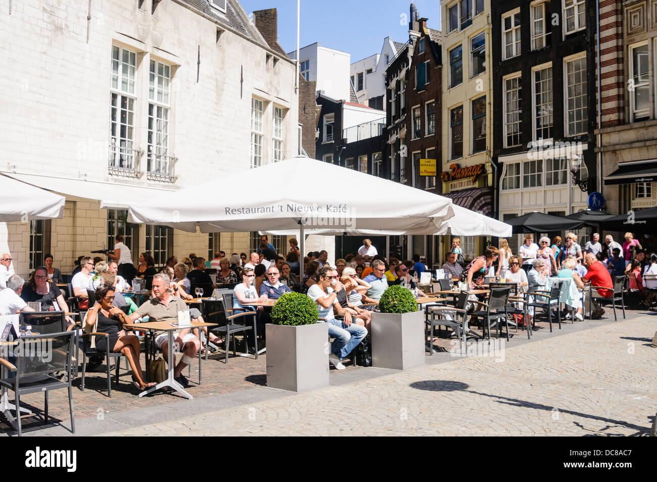 Le persone sedute a tavoli fuori un cafe al Neuwekerk in Piazza Dam, Amsterdam Foto Stock