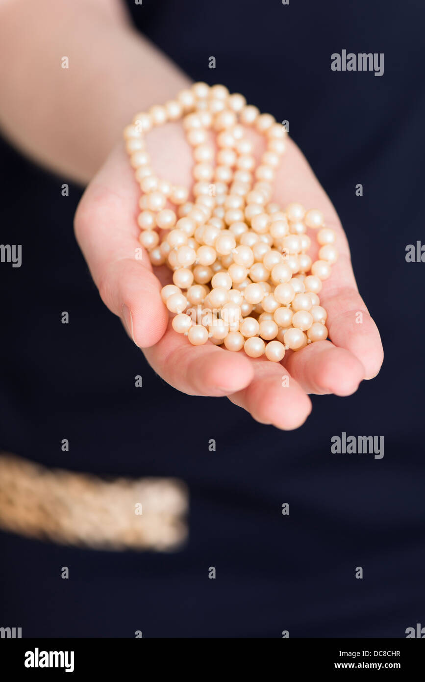 Giovane donna attesa collana di perle in mano Foto Stock