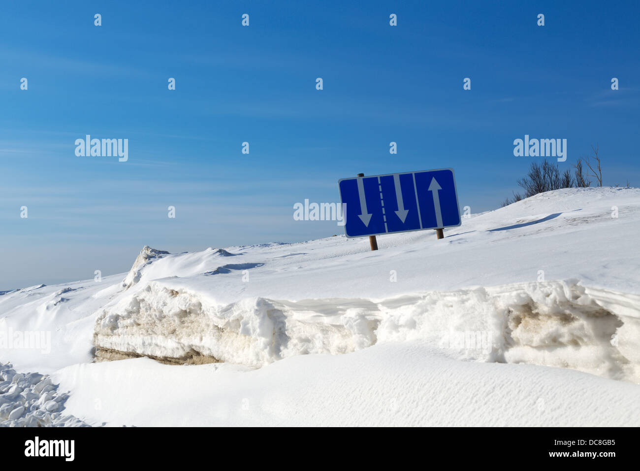 Segnale di traffico la separazione delle bande nella neve contro il cielo blu Foto Stock