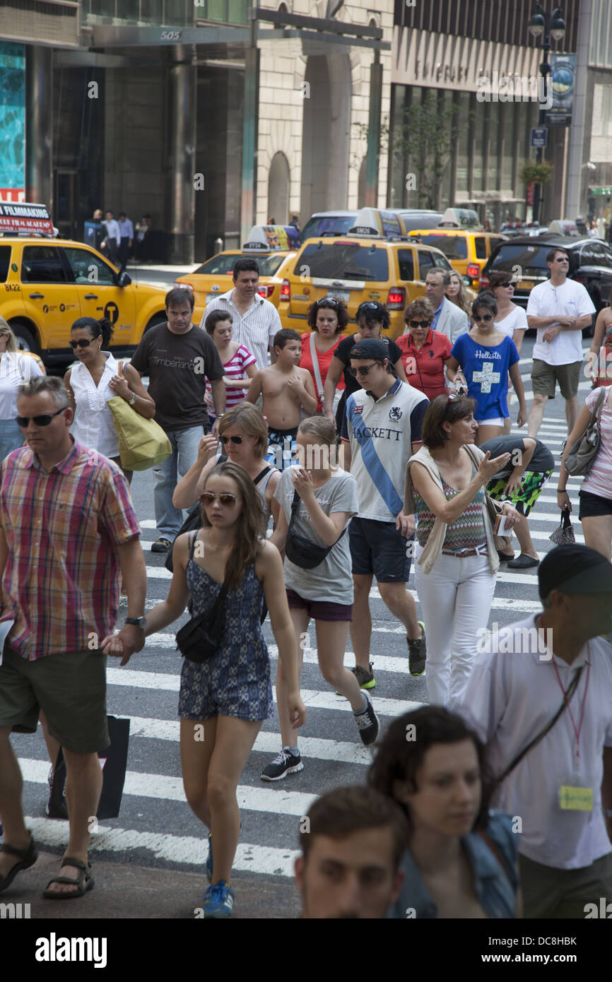 Persone barrare la strada al sempre affollato intersezione della Quinta Avenue & 42th Street, New York City. Foto Stock