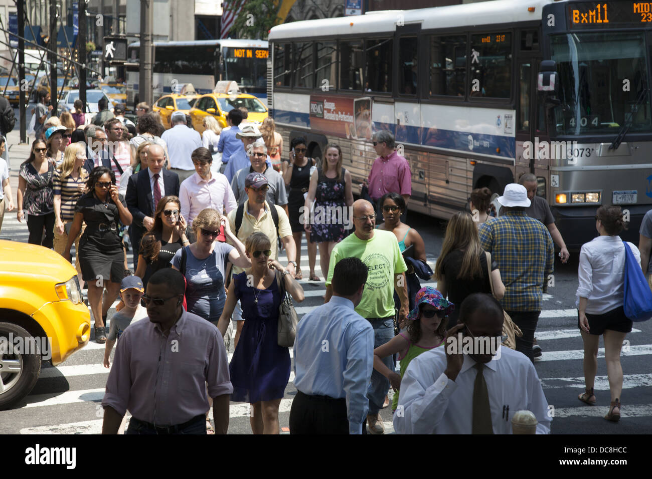 Persone attraversare la strada al sempre affollato intersezione della Quinta Avenue & 42th Street, New York City. Foto Stock