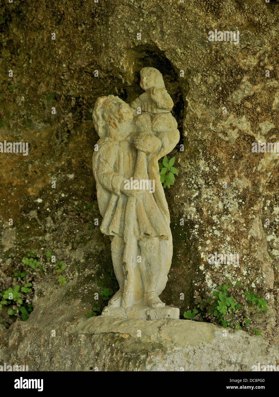 Antica statua in pietra di San Cristoforo e Gesù, cappella troglodita di La Roque Saint-Christophe, Dordogne, Francia. Foto Stock