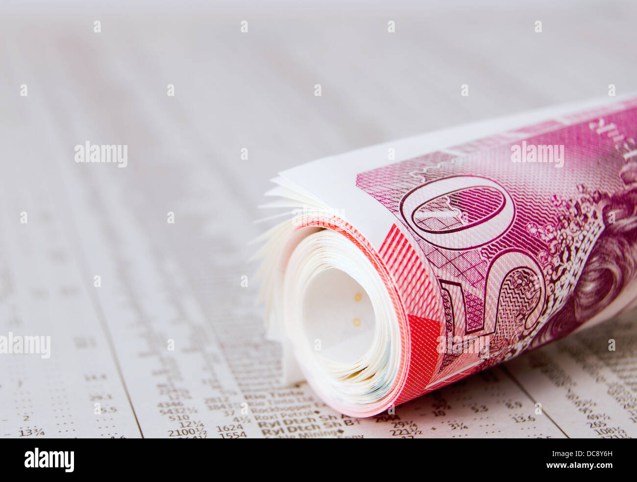 Rotolo di cinquanta pound note sul giornale che mostra condividono i prezzi Foto Stock